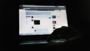 Homem em sala escura com o monitor do computador mostrando a página inicial da rede. Crédito: Dan Kitwood/Getty Images