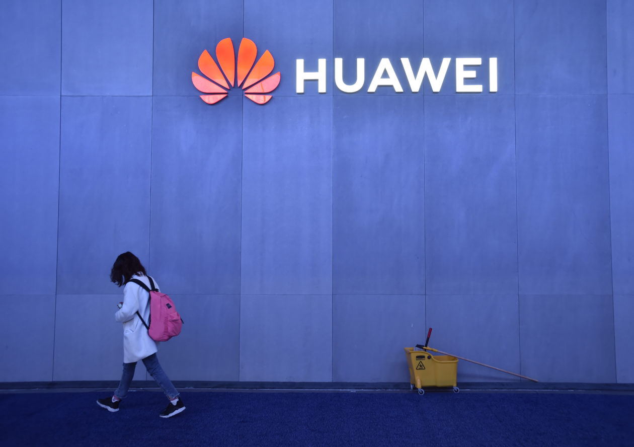 Pessoa caminha ao lado de logotipo da Huawei
