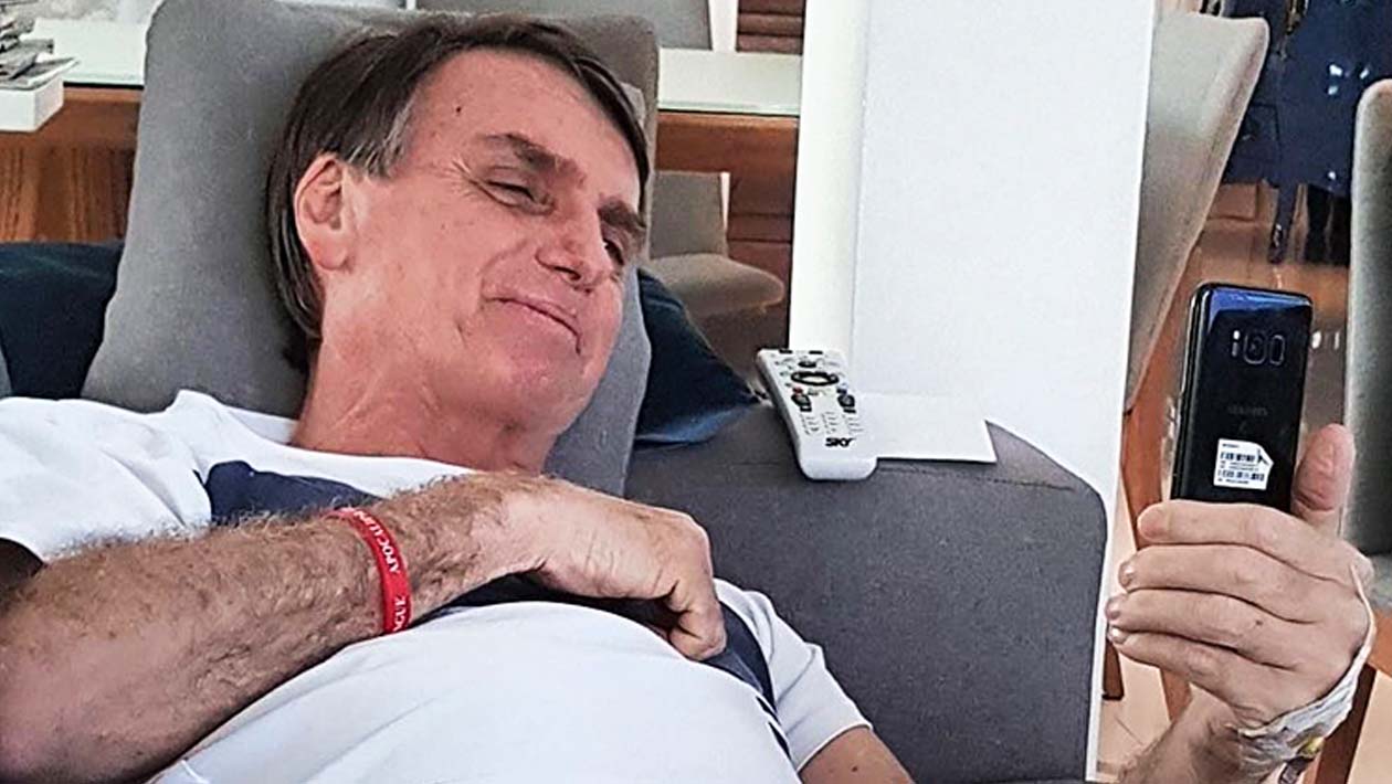 Jair Bolsonaro deitado e mexendo no celular