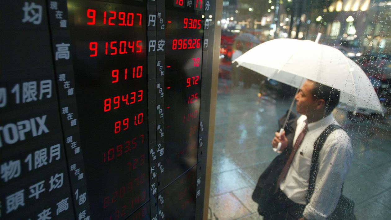 Homem olha preços de ações durante chuva em Tóquio, em 2002
