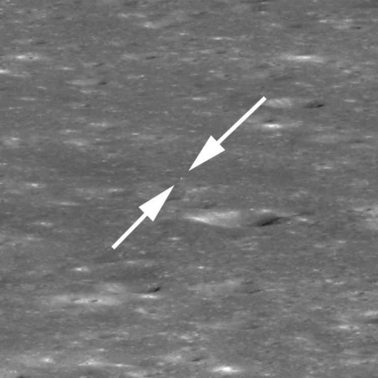 Duas setas brancas indicam o tamanho minúsculo do ponto na superfície lunar. Este ponto é a sonda Chang'e 4.
