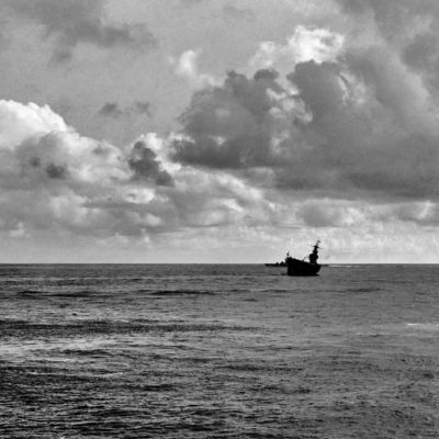 O porta-aviões USS Hornet no mar, visto de longe, um pouco inclinado.