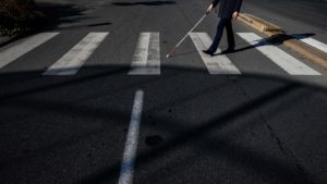 Homem atravessa na faixa de pedestre com bengala para cego