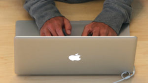 Homem usando laptop da Apple
