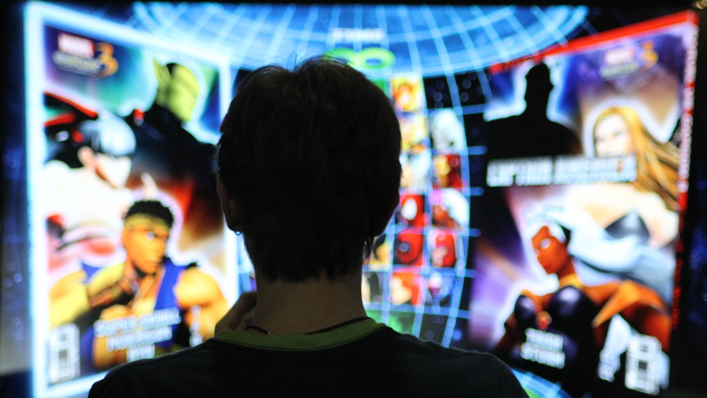 Garoto jogando Street Fighter em uma tela gigante