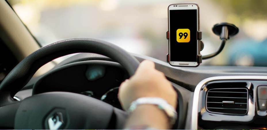 Motorista conduzindo um Renault com o app da 99 aberto no smartphone