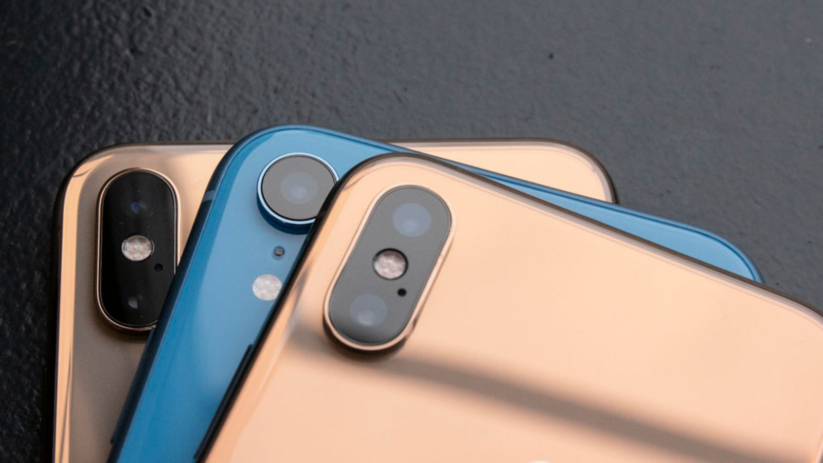 Dois iPhones XS dourados e um iPhone XR azul