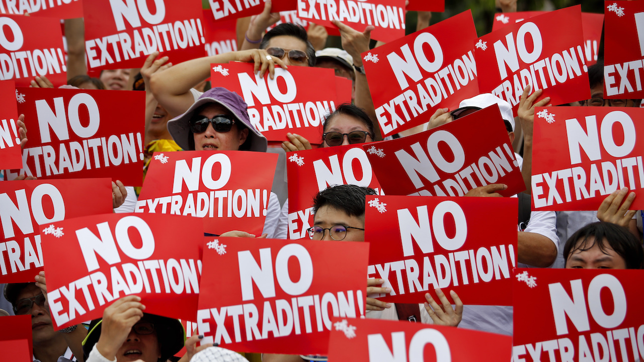 Manifestantes em Hong Kong seguram cartazes dizendo "No extradition"