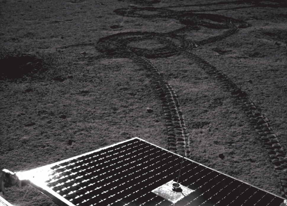 Trilha do rover Yutu 2, na Lua, junto com uma placa solar