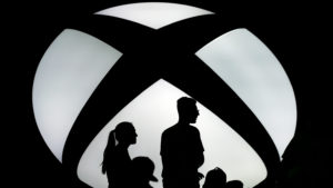 Logo do Xbox com silhuetas de uma família em frente dele.