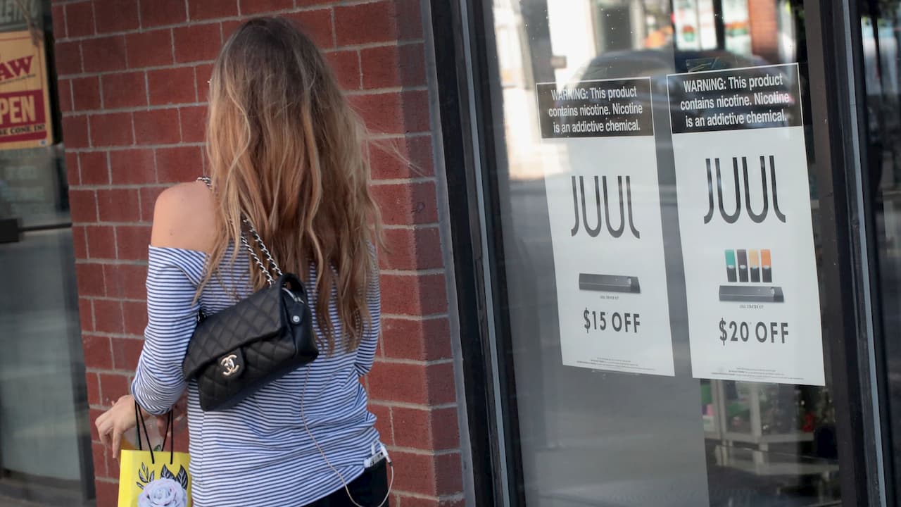 Mulher de costas passando em frente a uma loja da Juul