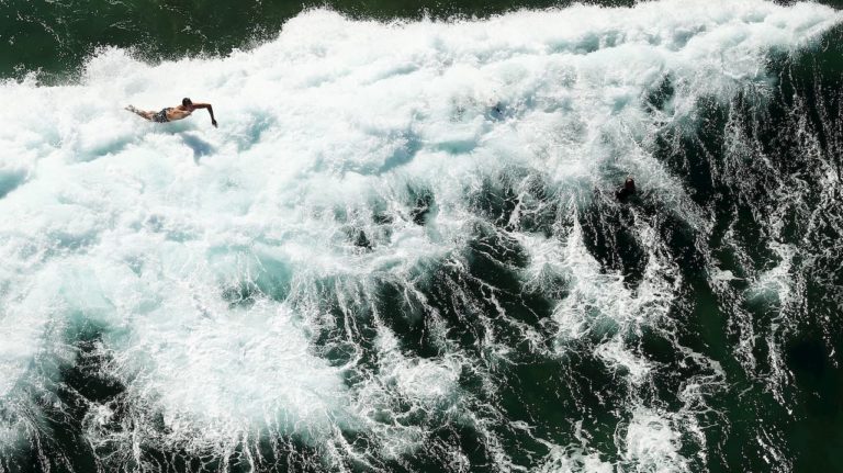 Ondas no mar e pessoa surfando.