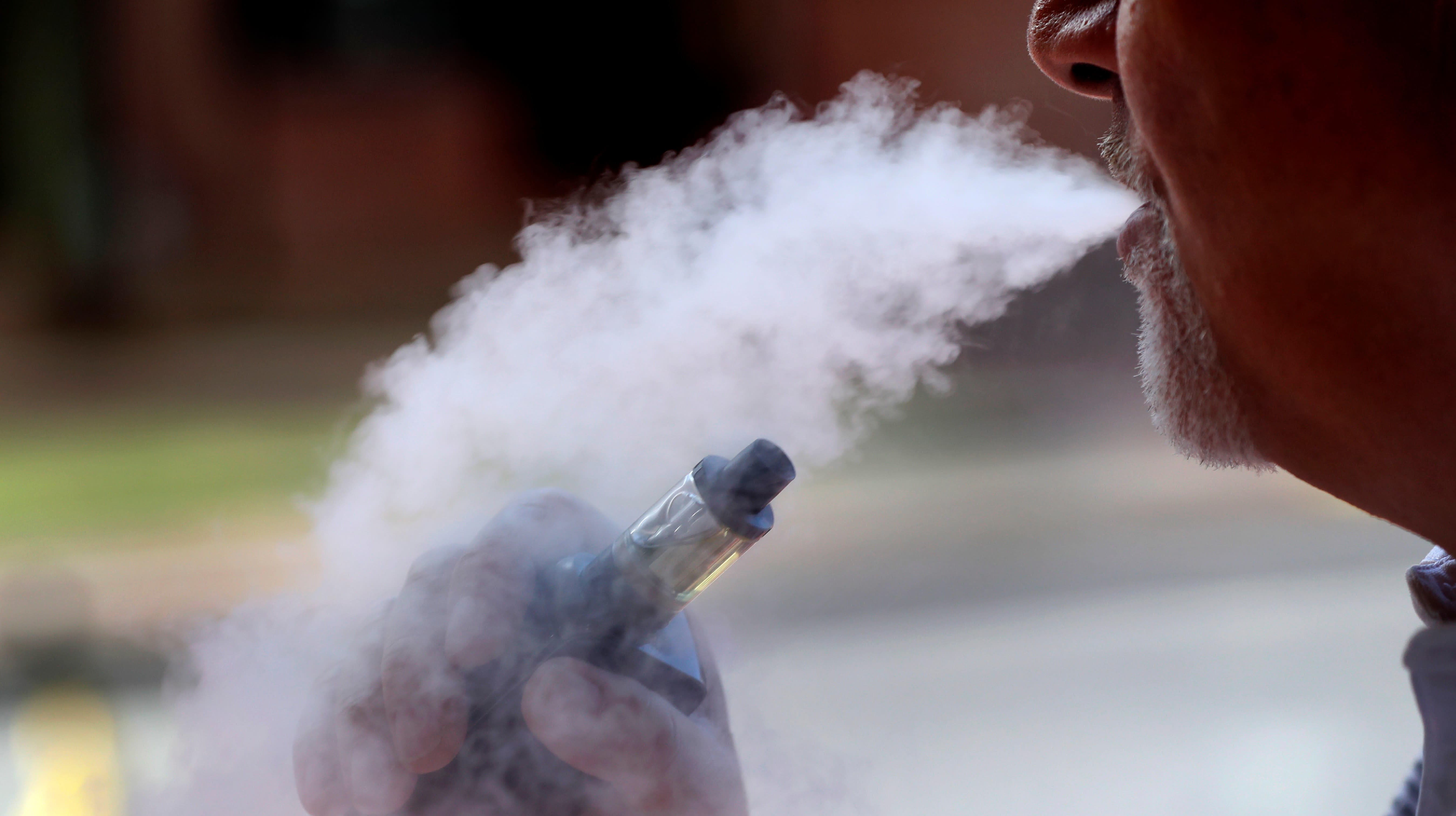 Homem expelindo fumaça após usar cigarro eletrônico/vaporizador