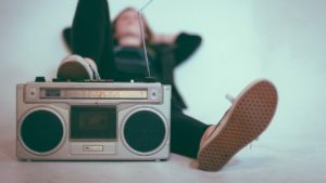 Jovem deitado com um pé sobre um rádio antigo.