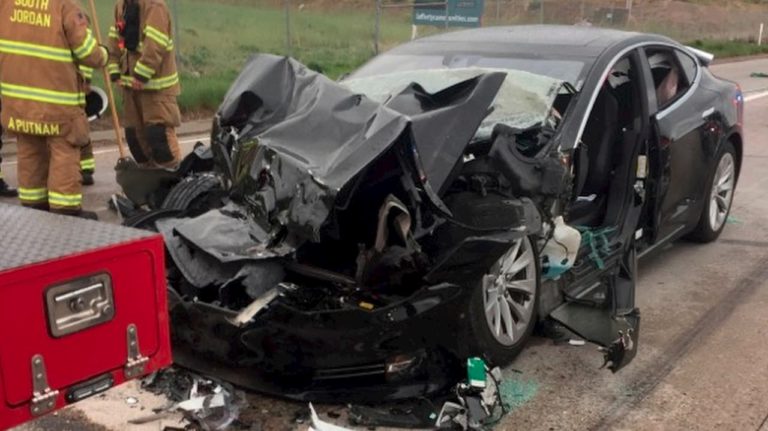 Carro elétrico da Tesla com a frente retorcida depois de colidir com um carro dos bombeiros.