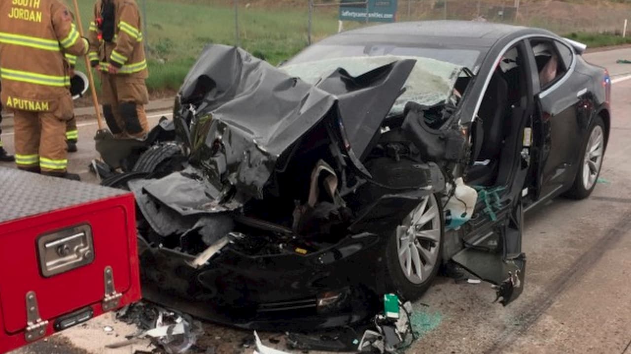 Carro elétrico da Tesla com a frente retorcida depois de colidir com um carro dos bombeiros.