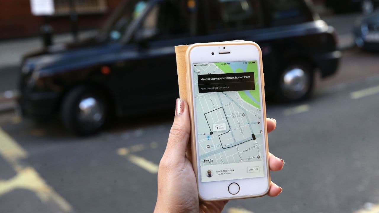Aplicativo da Uber em frente a um táxi de Londres