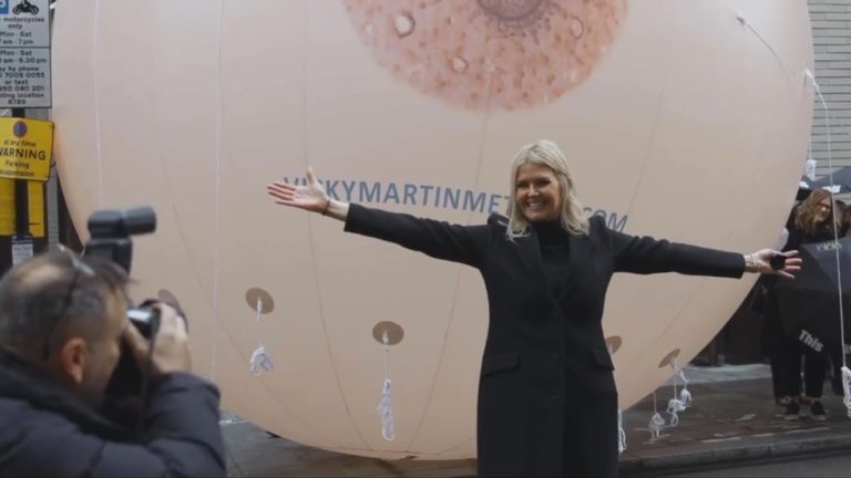 Vicky Martin protesta em frente a um seio inflável na sede do Facebook em Londres