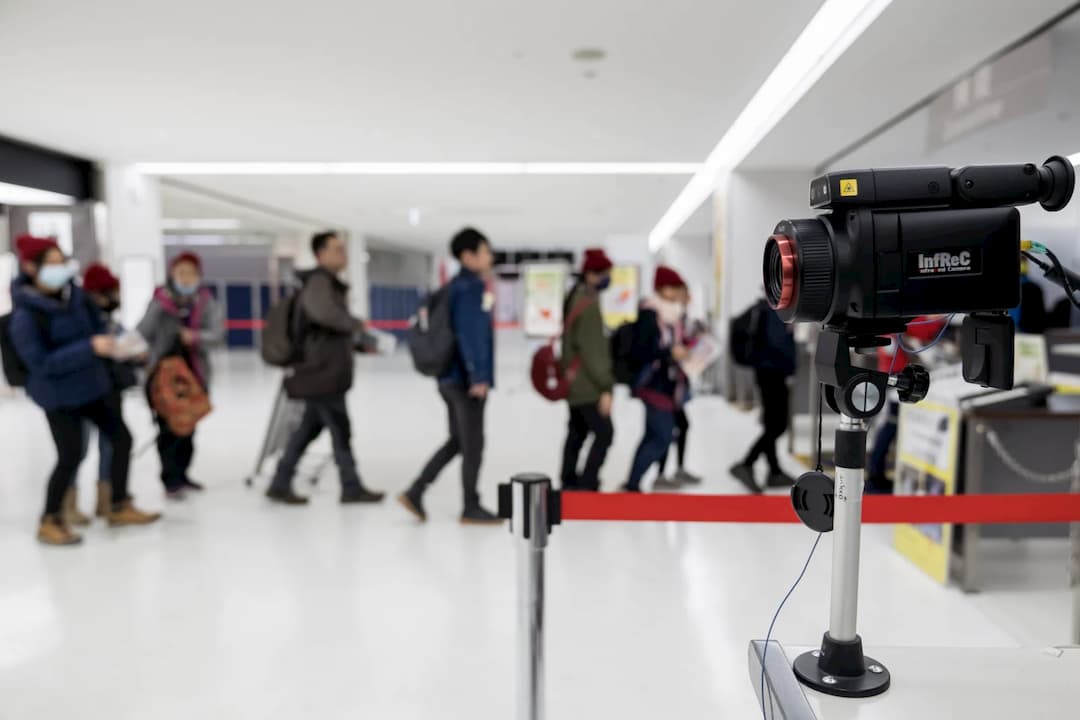 Viajantes passam por um scanner térmico durante a chegada ao aeroporto de Narita, em 17 de janeiro de 2020, no, Japão