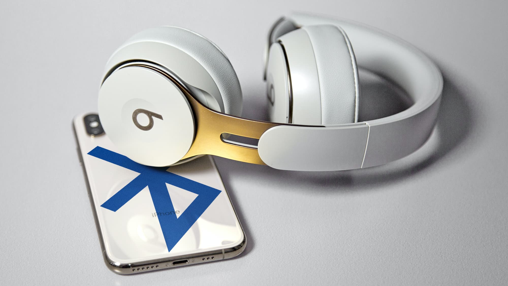 Montagem com traseira de um smartphone com o logo do Bluetooth e um fone Beats