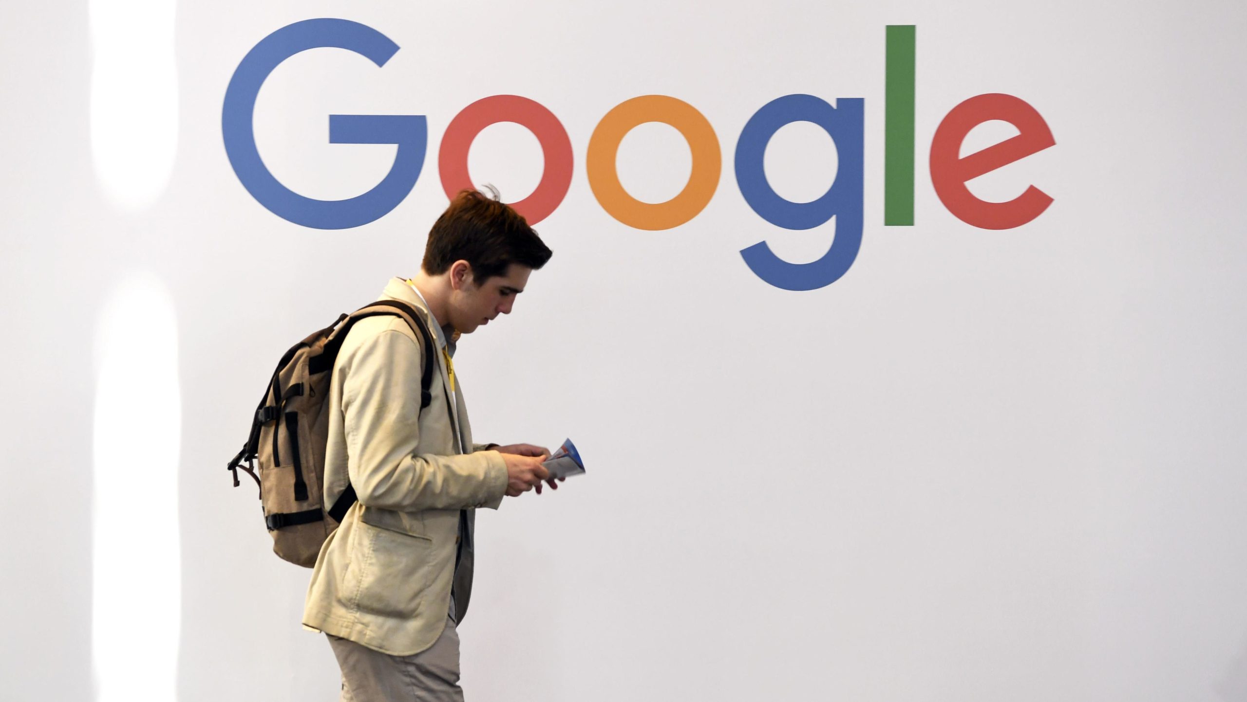 Homem passa em frente ao logotipo do Google. Crédito: Getty