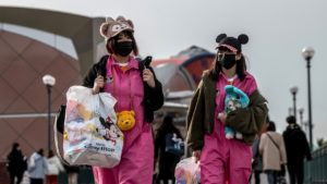 Mulheres usando máscaras descartáveis saem da Disneylândia de Tóquio