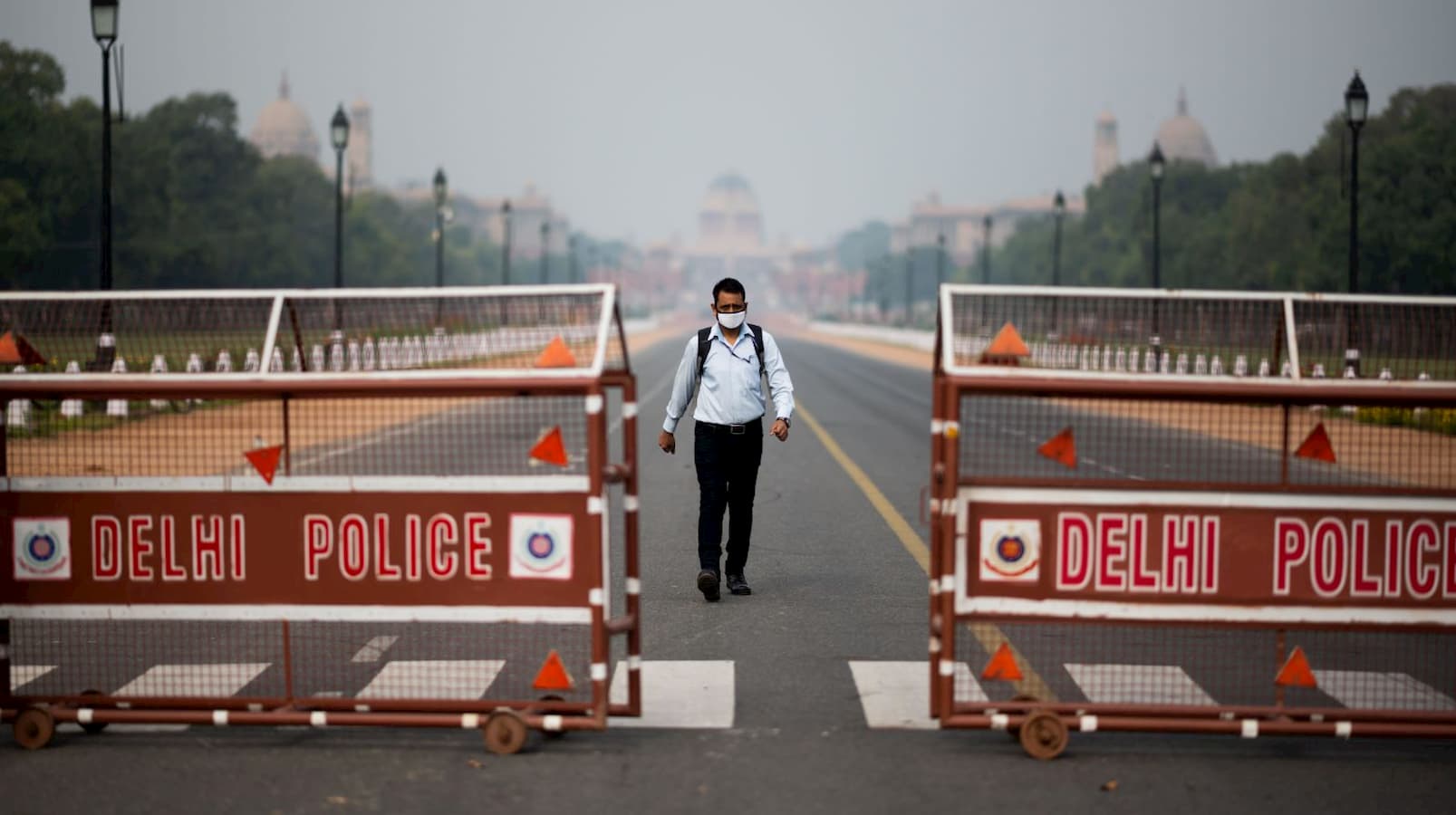 Homem caminha em rua deserta que leva ao Palácio Presidencial de Nova Deli, Índia