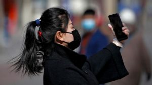 Mulher com máscara usando celular