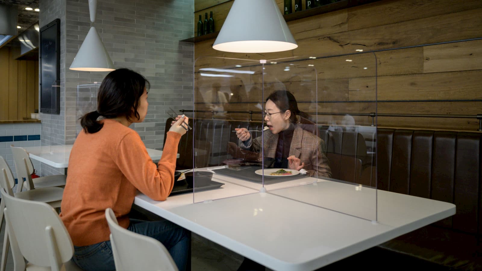 Pessoas comendo separadas por uma tela na Coreia do Sul