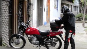 Motoboy mexendo no baú da moto na CIdade do México. Crédito: flickr/carlbcampbell/cc
