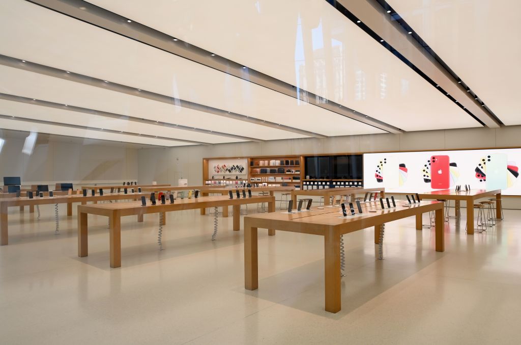 Loja da Apple fechada. Há várias mesas de madeira com produtos expostos. Ninguém está na loja.