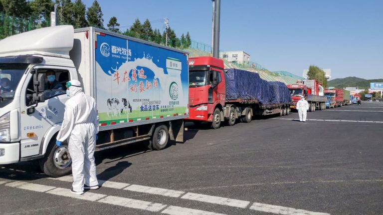 Funcionário usa equipamento de proteção e fala com caminhoneiro na saída de uma rodovia em Jilin, na província chinesa de Jilin, no dia 13 de maio de 2020.