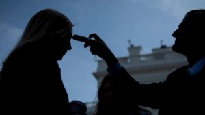 Mulher tem sua temperatura checada em frente a Casa Branca, nos EUA