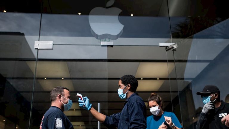 Funcionário verifica temperatura de um cliente na entrada de Apple Store