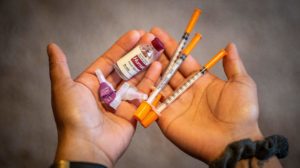 Pessoa segura seringas e ampola de insulina, kit usado em tratamento de diabetes. Crédito: Getty Images
