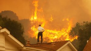 Um homem em um telhado olha para as chamas que se aproximam do incêndio de Springs em maio de 2013 perto de Camarillo, Califórnia.