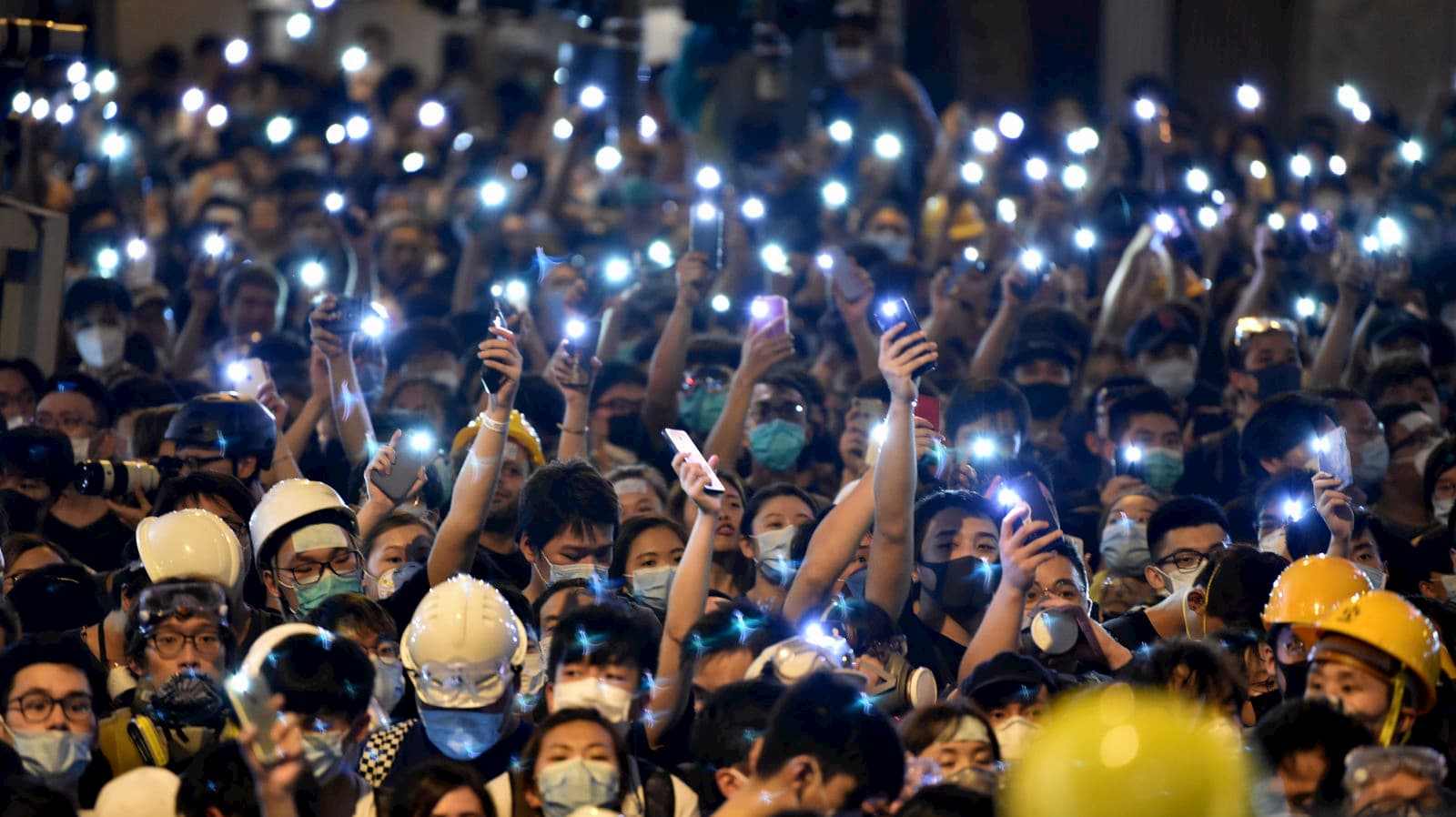 Protestantes em Hong Kong com as lanternas de seus celulares acesas.