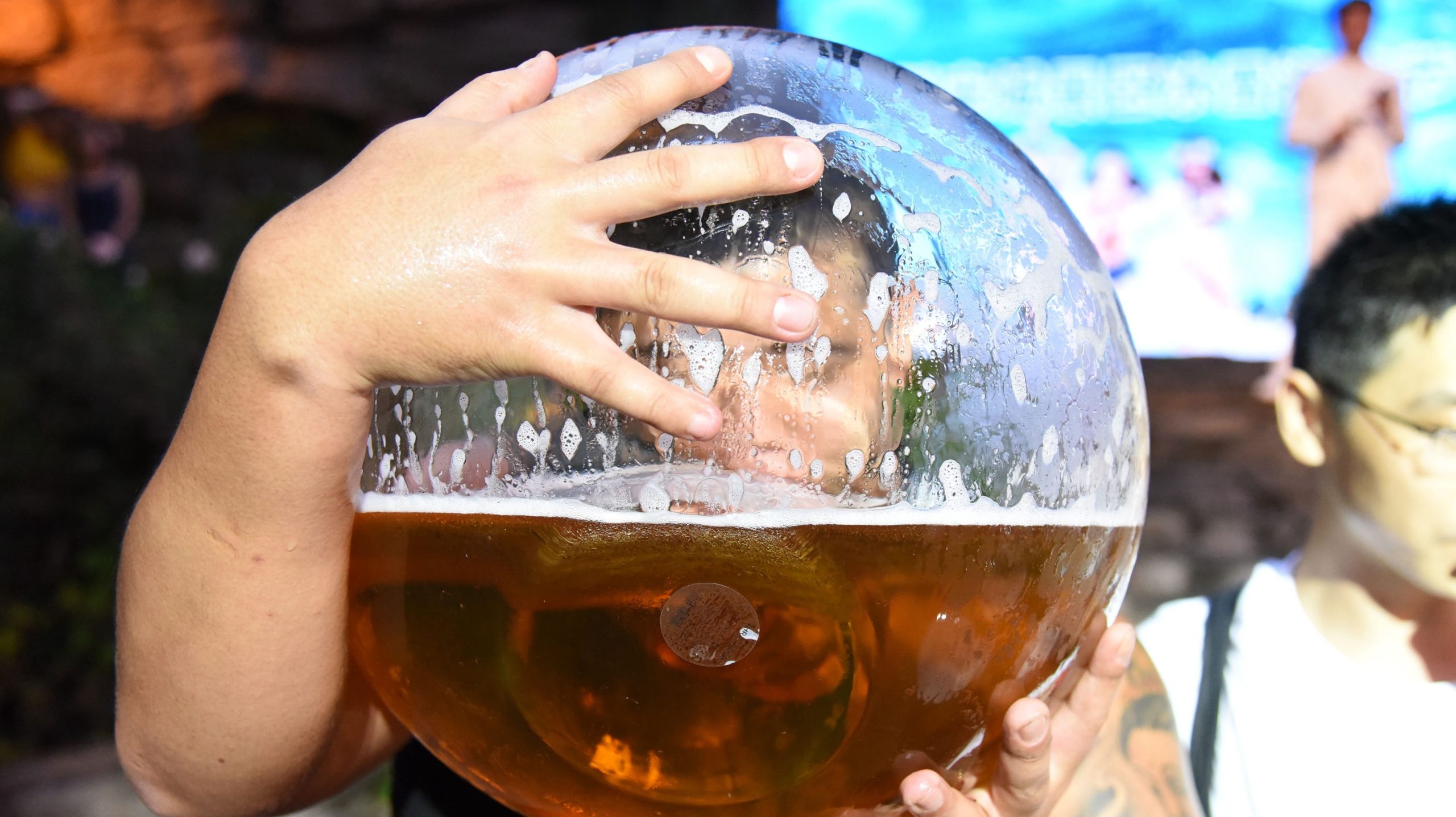 Homem bebendo cerveja em um copo gigante. Crédito: VCG/Getty Images
