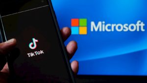 Pessoa segura aplicativo do TikTok sobre um fundo com logo da Microsoft