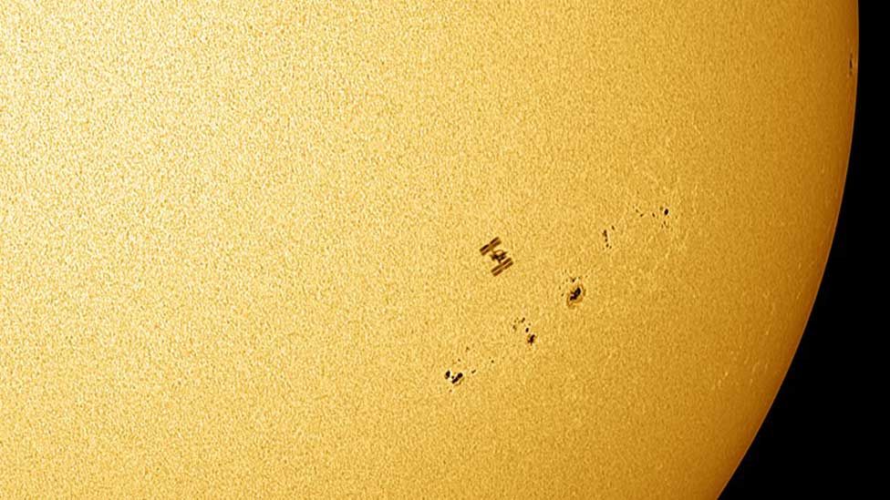 ISS é fotografada próxima a um grupo de manchas solares.