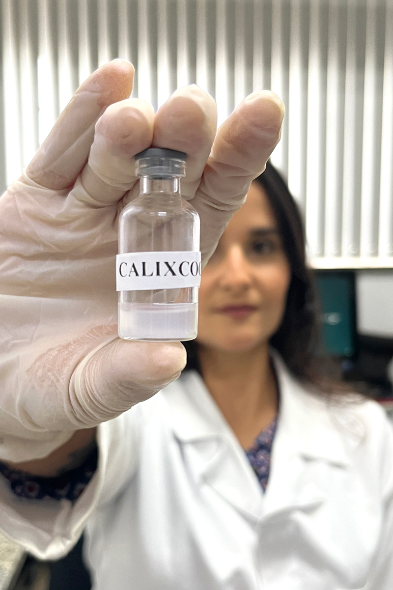 Pesquisadora da UFMG segura frasco contendo a formulação do imunizante Calixcoca