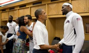 Barack Obama, conversa com LeBron James enquanto a primeira-dama Michelle Obama abraça Deron Williams durante sua saudação com membros da equipe olímpica masculina de basquete dos EUA no intervalo do jogo contra o Brasil no Verizon Center em Washington, DC, 16 de julho de 2012.