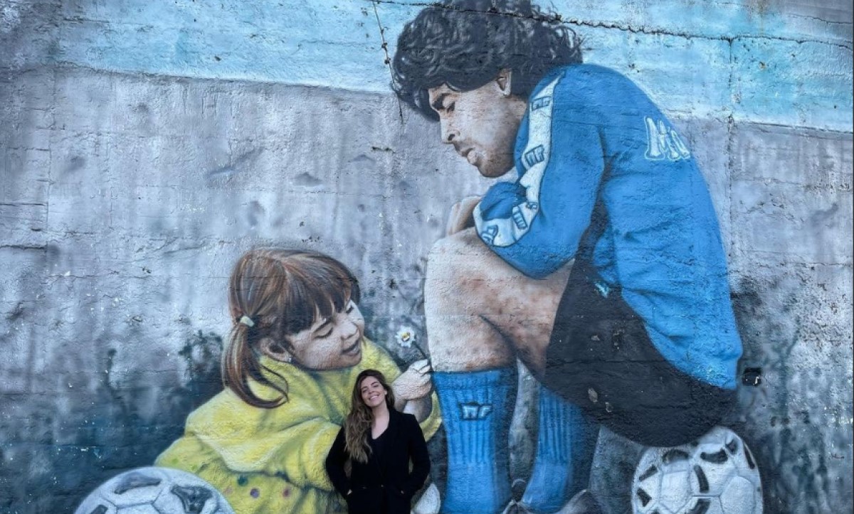 Dalma Maradona diante de mural com foto dela e do pai, Diego Maradona