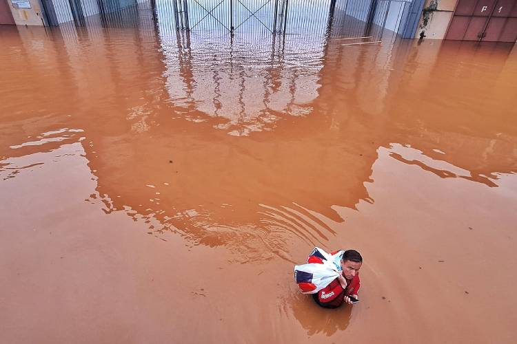 Homem atravessa área alagada em Porto Alegre (RS); contato com água contaminada é a principal fonte de doenças em caso de enchentes