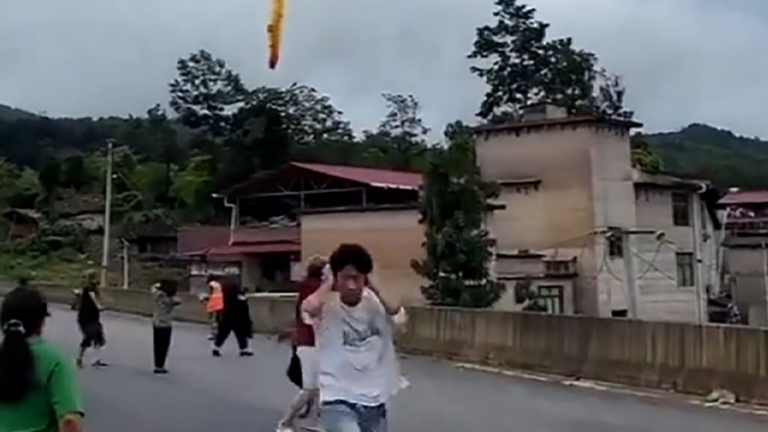 Pessoas correndo da área de colisão do foguete chinês caindo do céu